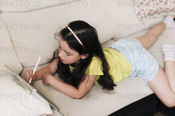 Girl laying couch drawing tablet