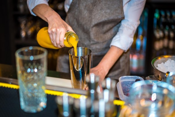 Close-up of an unrecognizable female bartender using juice to prepare a luxury cocktail