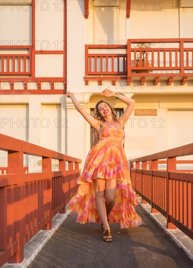 Vertical photo of a woman dancing happily with long dress during sunset outdoors