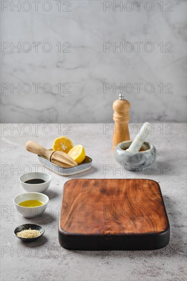 Empty wooden chopping board surrounded with kitchen utensils and bowls