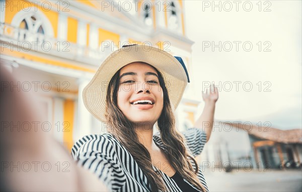 Lifestyle of tourist girl in hat taking a selfie in a square. Granada