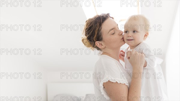 Beautiful mother kissing baby girl