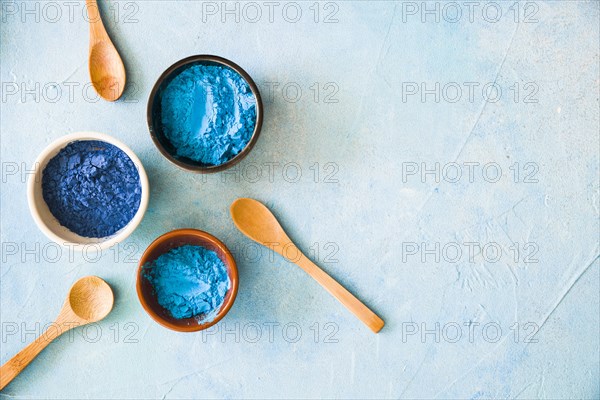 Bowls with holi color powder wooden spoon painted background