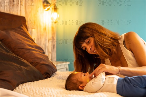 Mother and baby boy resting lying on the bed in an hotel room