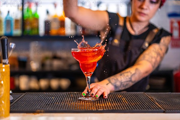 Cocktail splashing while a bartender mixing ingredients in the counter of a bar