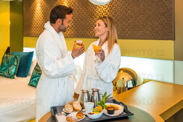 Lovers talking relaxed wearing bathrobe while having breakfast in the room of a luxury hotel
