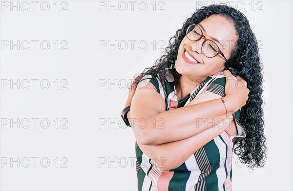 Smiling young woman hugging herself with self love. Self love concept. Afro woman hugging herself isolated