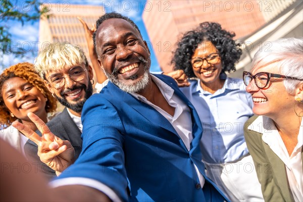 Frontal view of happy elegant african businessman taking a selfie with coworkers