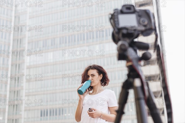 Brunette blogger drinking water from bottle