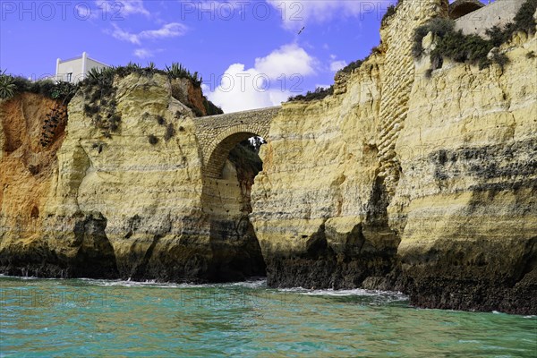 Historic Roman stone bridge at Praia da Batata beach in the rocky coast of Lagos