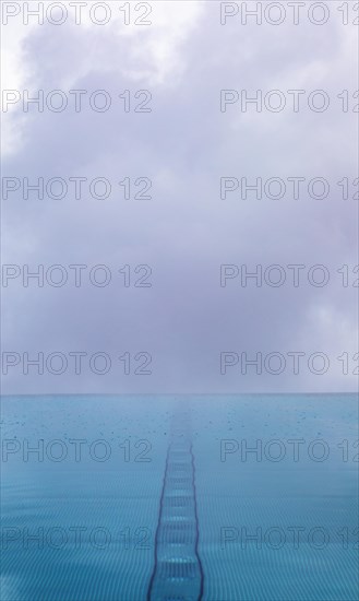 Rippled water surface during rain in swimming pool with dramatic cloudy sky