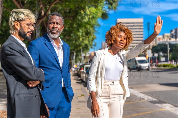 African businesswoman asking for a taxi waiting with colleagues on the street