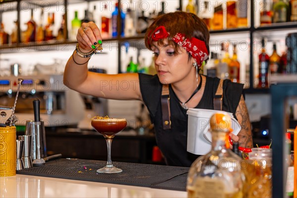 Bartender decorating the top of a cocktail in the counter of a bar