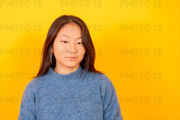 Studio photo with yellow background of a chinese young woman smiling at camera