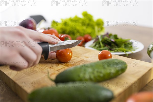 Close up hand cutting tomato with knife