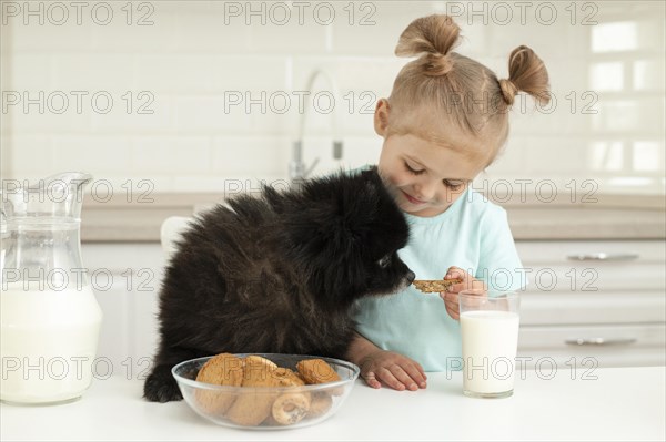 Girl drinking milk playing with dog home