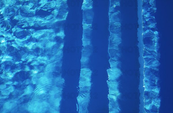 Water surface with light reflections and pool stairs in a swimming pool