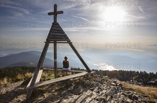 Hiker sitting at the Berger Alm weather cross on the Gerlitzen