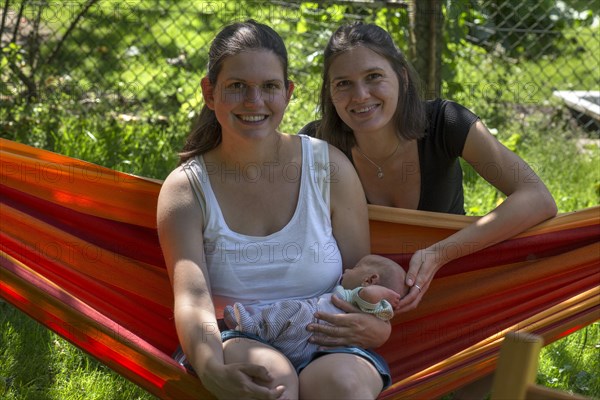 Young mother with baby in a hammock in the garden