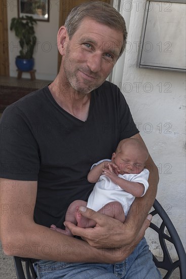 Young grandpa with his newborn grandson in his arms