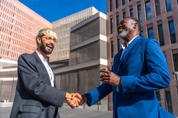 Multi-ethnic business people in suit shaking hands to secure a deal outside a financial building in a sunny day