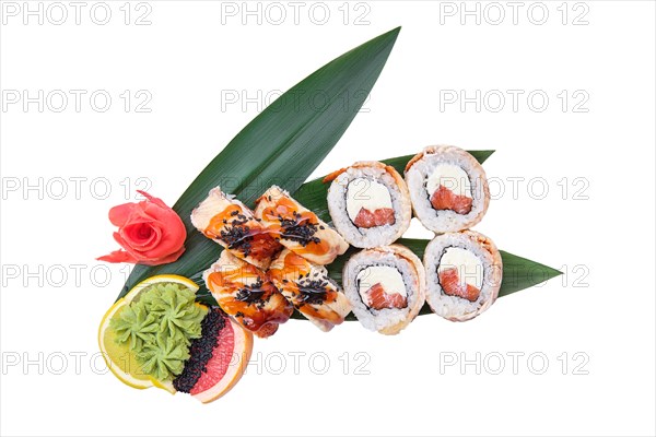 Overhead view of roll with salmon with cream cheese and shrimp on top served on bamboo leaves