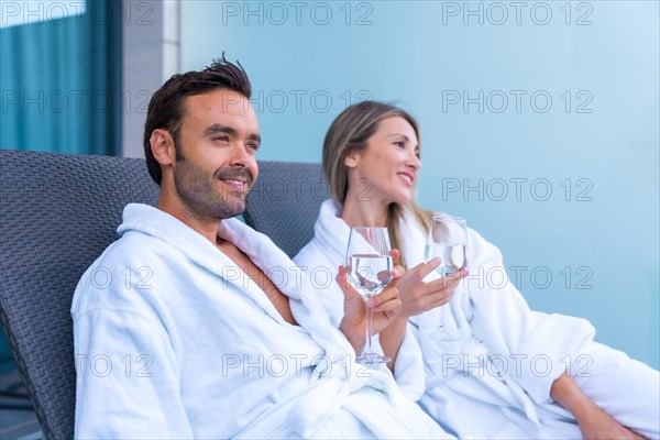 Relaxed couple in bathrobe drinking wine in the terrace of an hotel room