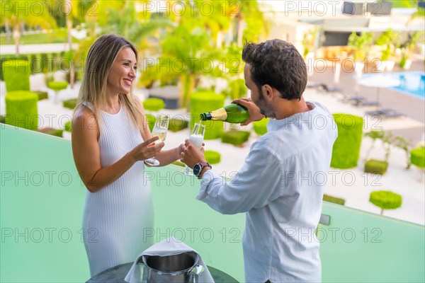 Happy couple drinking champagne in a luxury terrace of an hotel