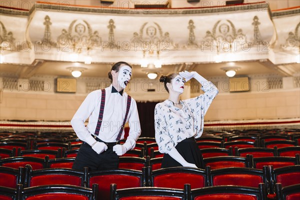 Male mime looking female mime looking up auditorium
