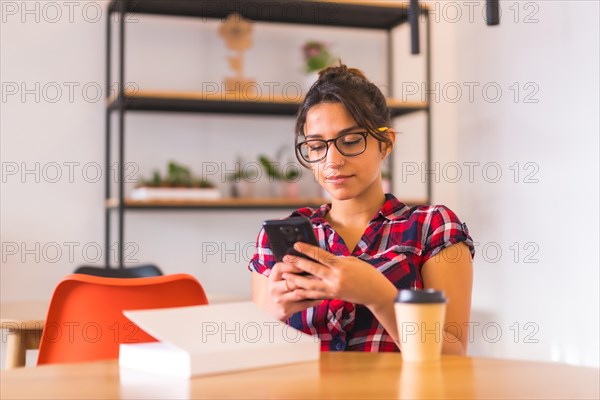 Relaxed woman doing weekend activities as using phone and reading a book at home