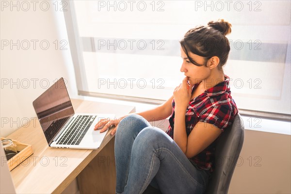 High angle view of a woman sitting on a desk using laptop at home