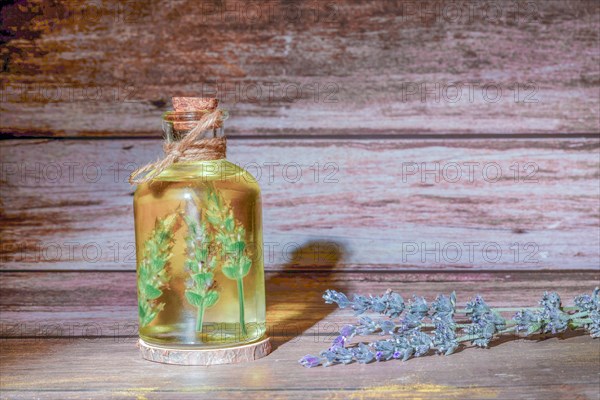 Glass bottle with lavender oil with lavender branches inside on a wooden table