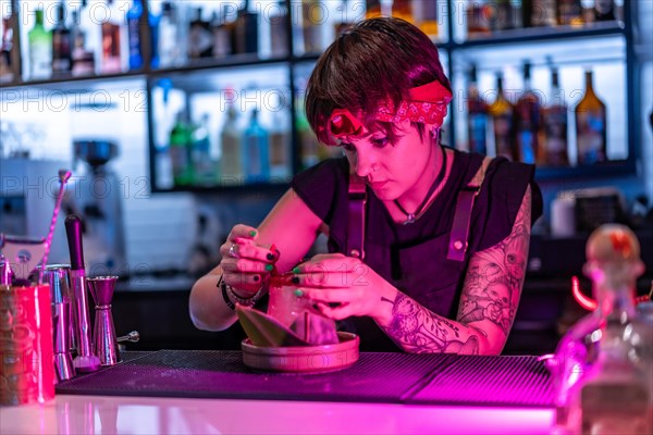 Concentrated young female bartender decorating a cocktail in the counter of nightclub