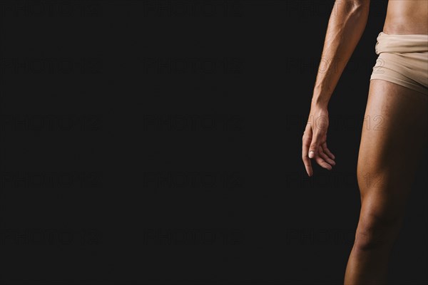 Athletic naked male standing against black background