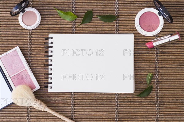 Blank spiral notepad surrounded with cosmetics products placemat