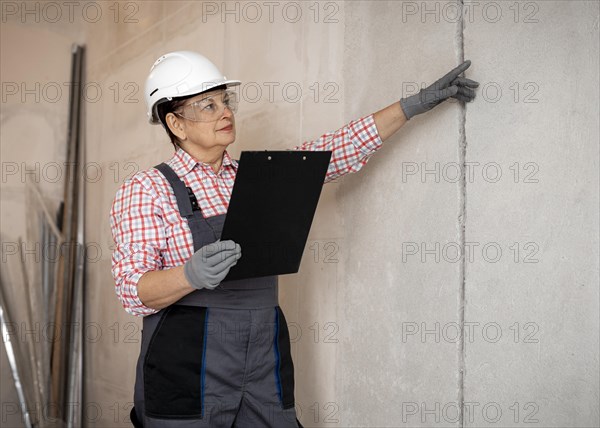 Female construction worker with helmet inspecting with clipboard