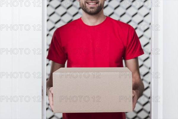 Front view delivery man wearing red uniform close up box