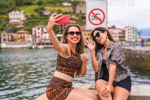 Friends having fun taking a selfie next to a prohibition panel sign in a promenade
