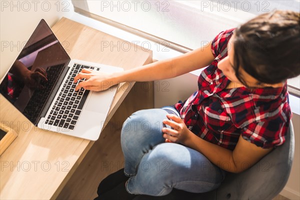 Top view of a woman working from home using laptop sitting on a desk