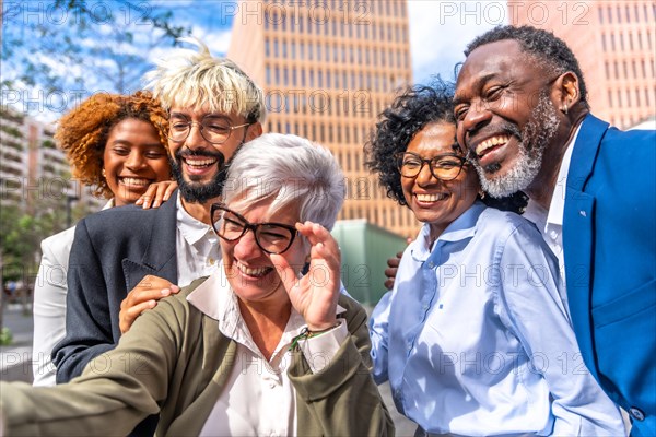 Side view of a happy mature businesswoman taking a selfie with colleagues outdoors