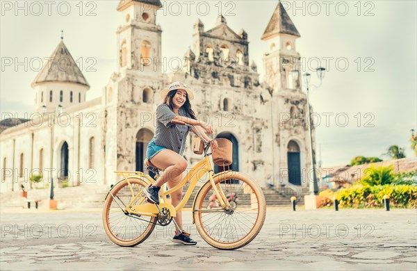 Happy girl in hat riding a bicycle at sunset. Tourism and travel concept. Lifestyle of a happy girl in hat on bicycle on the street. Granada