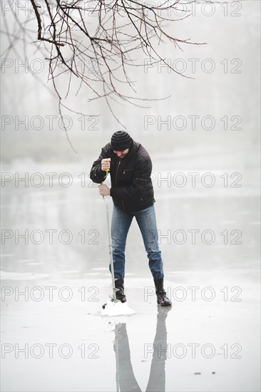 Winter fishing frozen lake with hand drill