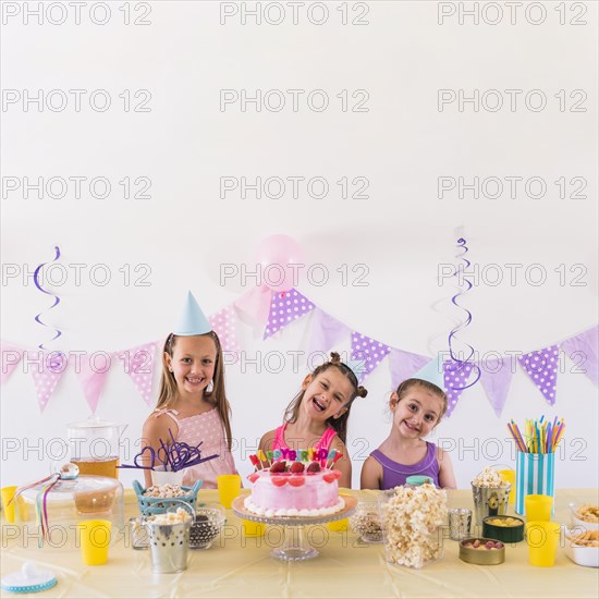 Happy friends enjoying birthday party with tasty snack cake table