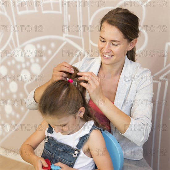 Medium shot smiley teacher tying girl s hair