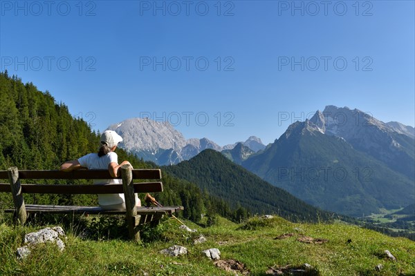 Hiker on a bench at the Mordaualm enjoying the view of the Watzmann and Hochkalter