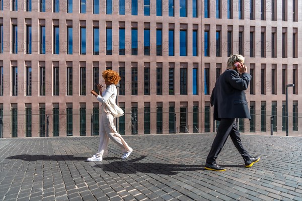 Side view of two business people walking commuting to the office