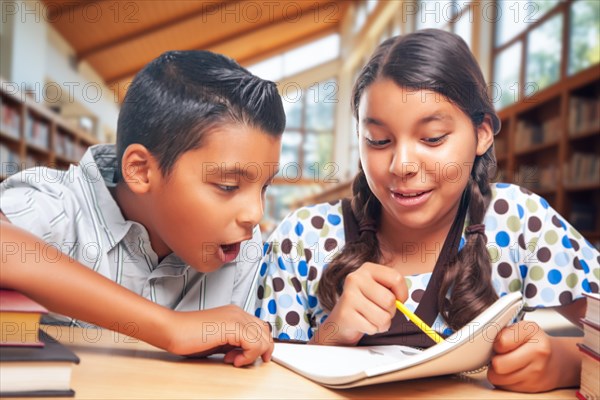 Hispanic school kids doing homework together in the library