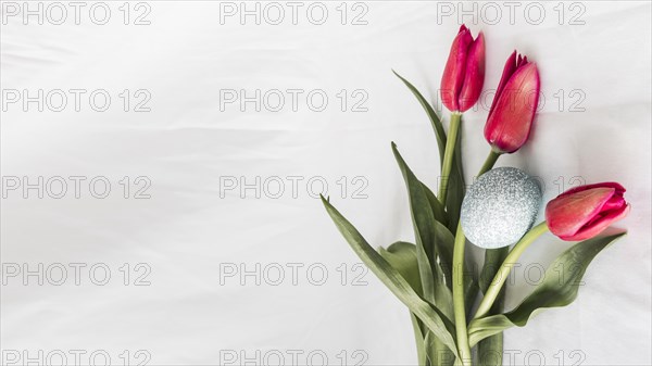 Easter egg near bunch flowers