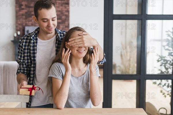 Male with gift closing eyes woman