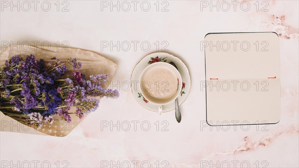 Notebook with coffee cup flowers bouquet table